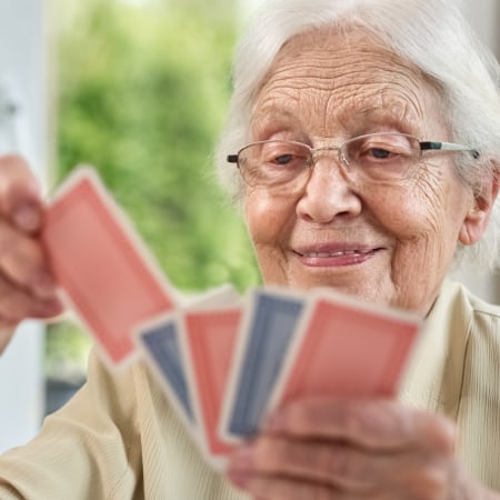 Mature woman slightly smiling holding playing cards in hand